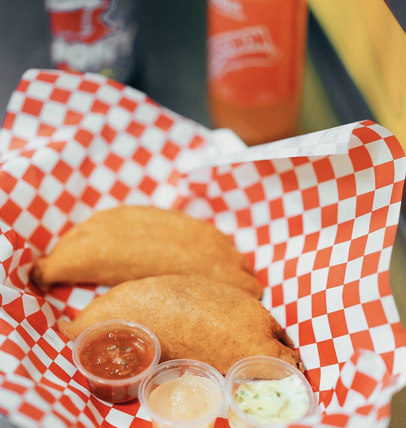 Golden crispy empanadas in a basket with dipping sauces